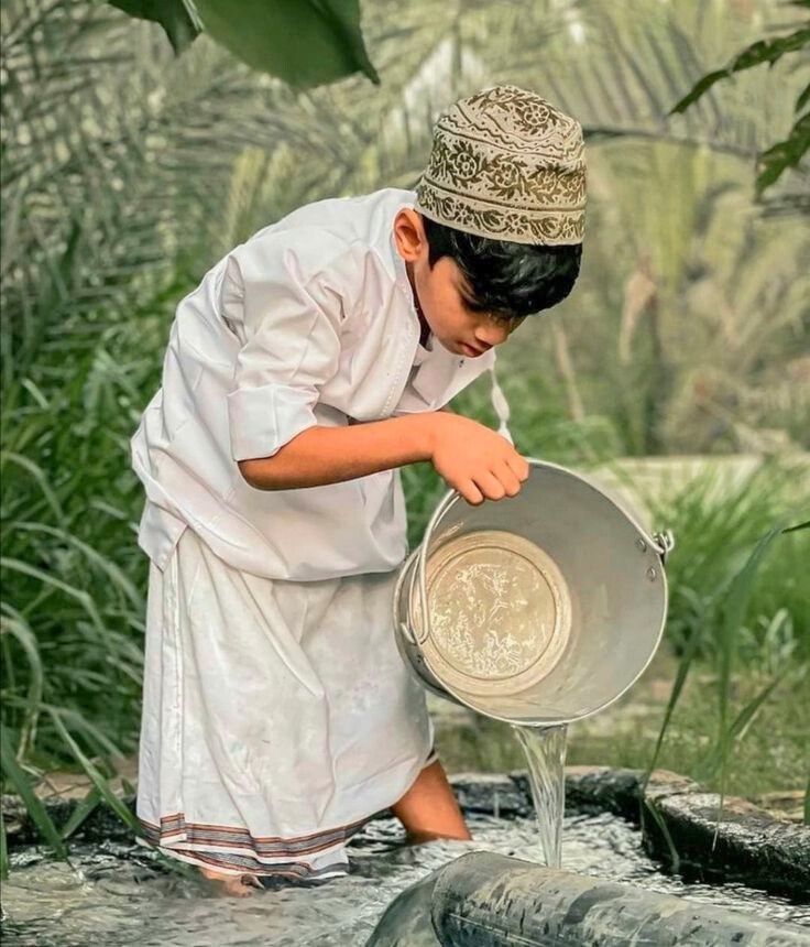 Omani boy pouring water — sustainable tourism